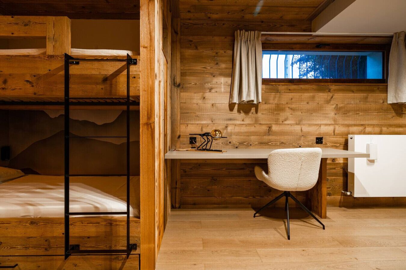 Un intérieur en bois avec des lits superposés, un bureau et une chaise.
