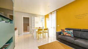 Una sala de estar moderna con un sofá, un comedor con sillas y una escalera.