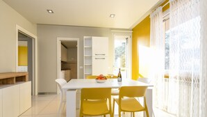 Una cocina moderna con armarios blancos, una mesa de comedor blanca y sillas amarillas.