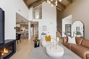 Un vaste espace de vie doté d’une cheminée, d’un canapé en cuir marron, d’une table basse ronde et d’un escalier menant à un niveau supérieur.