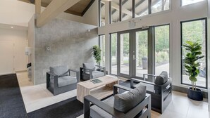 A spacious living room with a high ceiling, large windows, and modern furniture. - Mountain Luxe | 4BDR Verbier | Jacuzzi & Sauna (Mont-Tremblant)