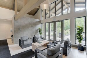 Un salon spacieux avec un haut plafond, de grandes fenêtres et un mobilier moderne.