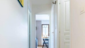 A hallway with wooden flooring, white walls, and a door on the right. - Bright T2 in the heart of Fontenilles (Fontenilles)