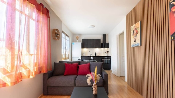 A modern living room with a sofa, a coffee table, and a kitchen in the background. - Bright T2 in the heart of Fontenilles (Fontenilles)