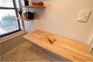 A kitchen with a wooden countertop, a cutting board, a knife, a kettle, and a shelf with kitchen items. - Luxury 1BR Sanctuary in Prime Jersey City Spot (Jersey City)