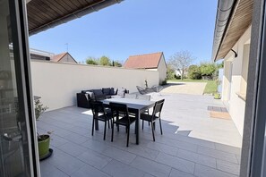 Eine Außenpatio mit Esstisch und Stühlen, einer Sitzecke und einem kleinen Gartenbereich.