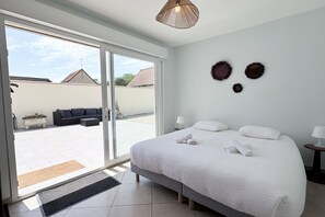Ein Schlafzimmer mit einem großen Bett, einer Schiebetür zu einer Terrasse und einer Wandleuchte.