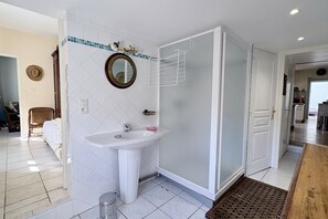 Ein Badezimmer mit einem weißen Waschbecken, einem Spiegel und einer Duschkabine aus Glas.