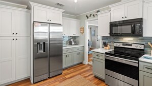 Una cocina moderna con armarios blancos, electrodomésticos de acero inoxidable y salpicadero de azulejos.