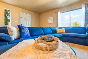 Ein Wohnzimmer mit einem blauen Sofa, einem gewebten Korb und einer Tür.