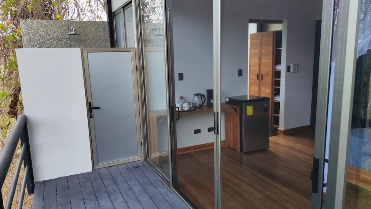 A modern apartment with a sliding glass door entrance, a small kitchen area, and a wooden deck.