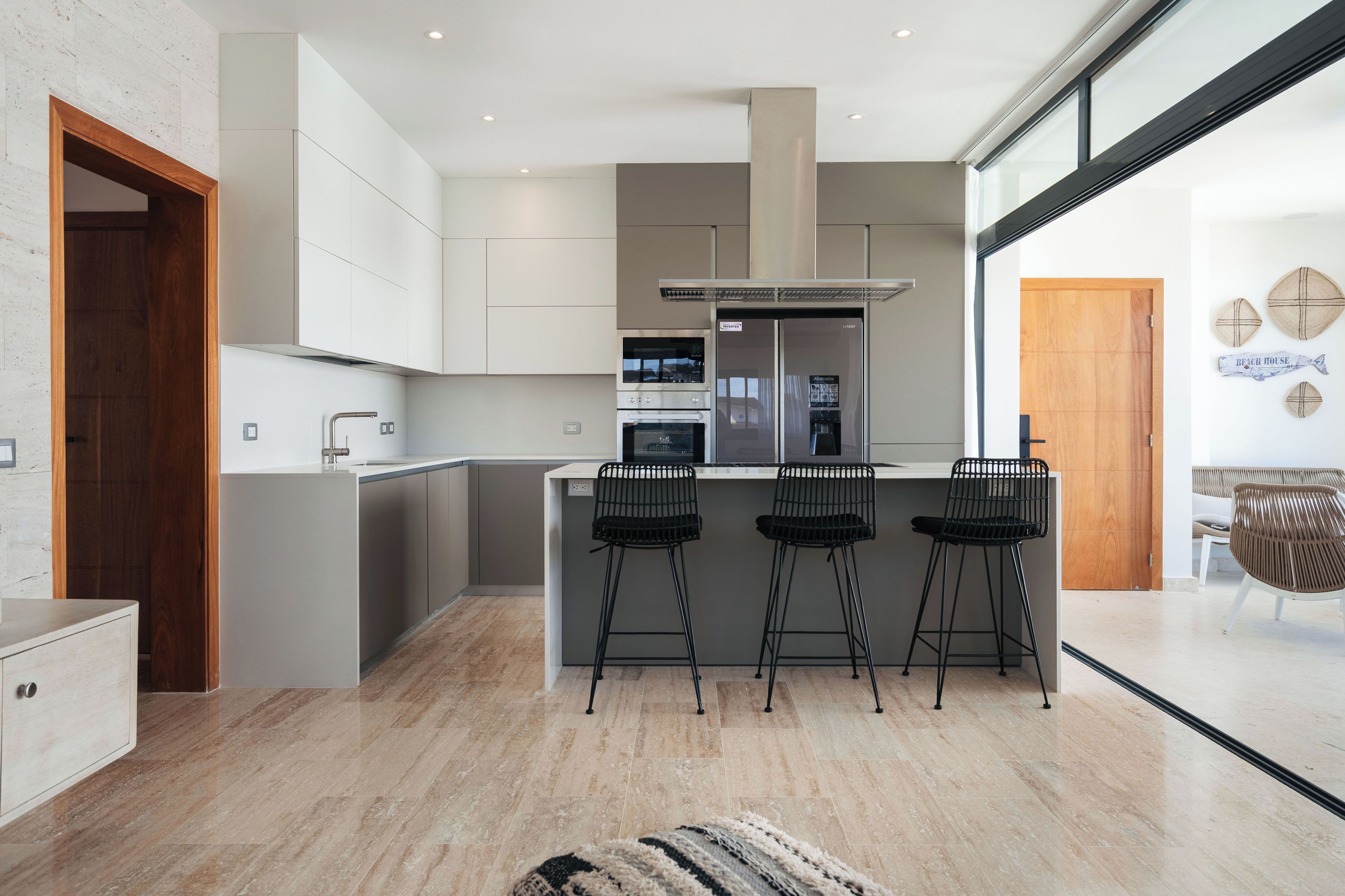 A modern kitchen with a central island, bar stools, and a view of the living area.