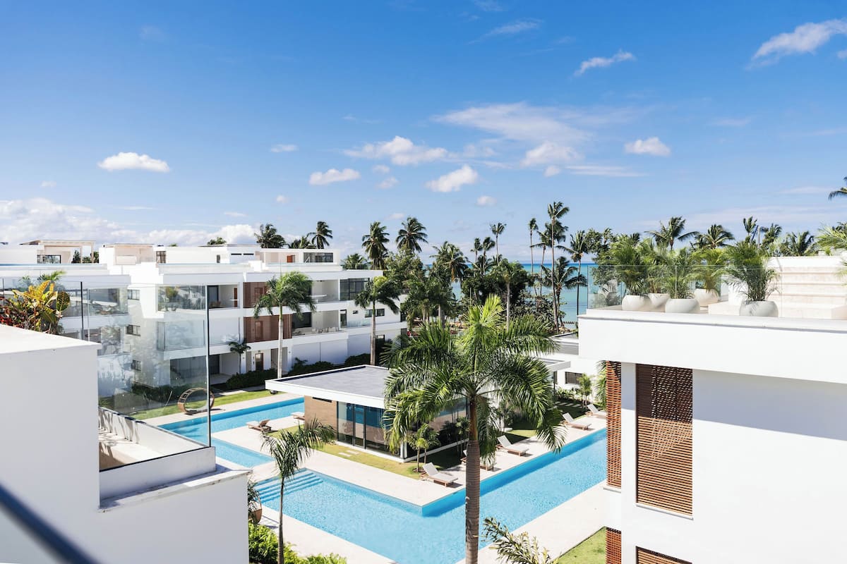 A modern resort with a pool area, palm trees, and white buildings.
