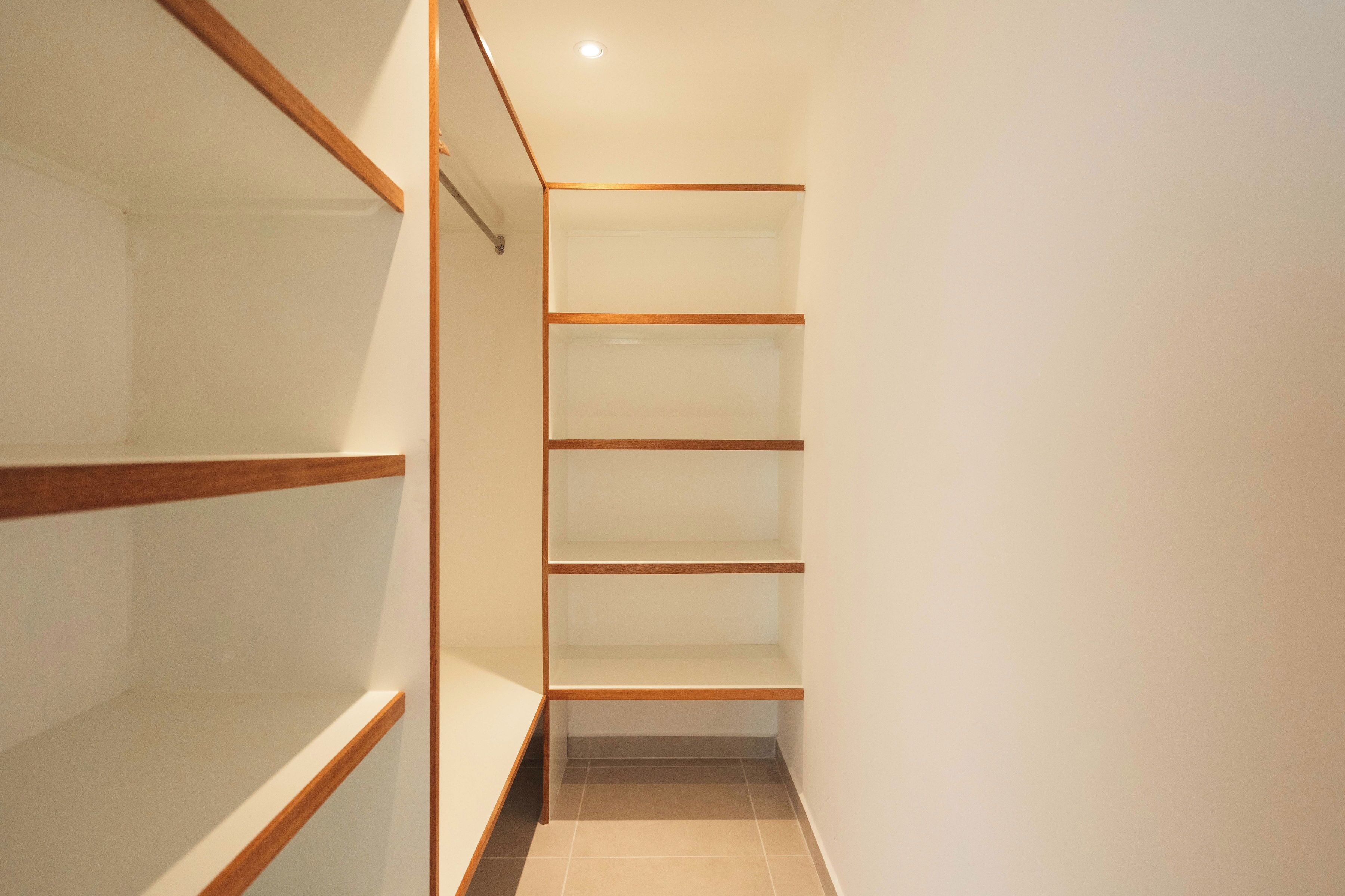 A narrow hallway with wooden shelving units and a tiled floor.