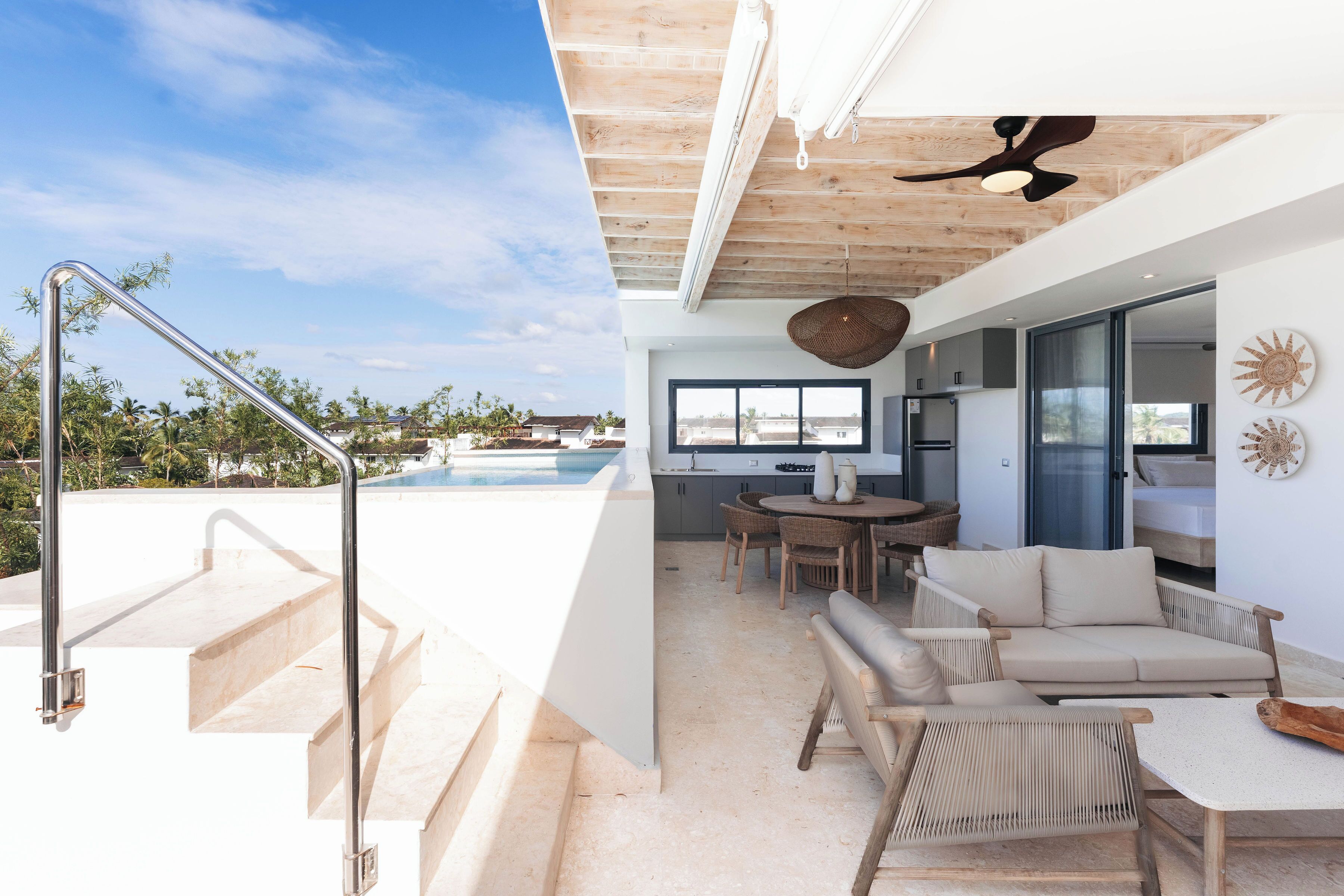 Ein modernes Interieur mit Pool, Sitzgelegenheiten im Freien und einer Treppe, die zu einem Balkon führt.