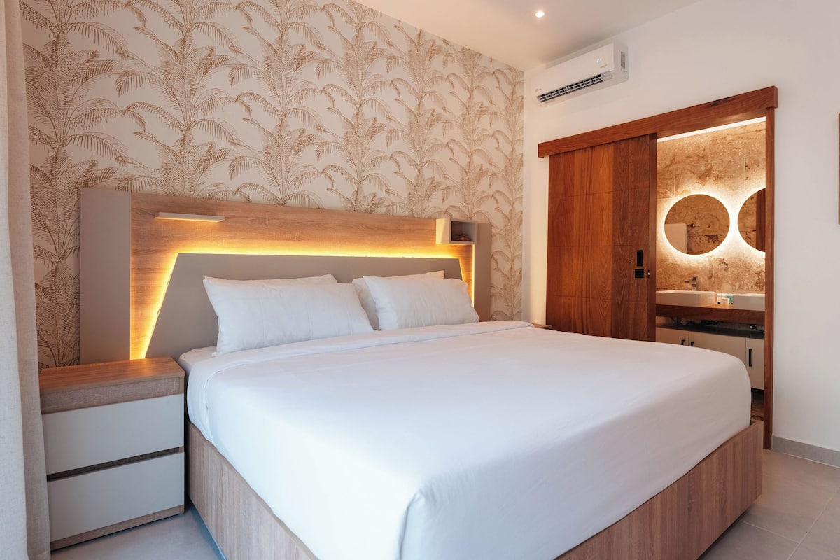 A modern bedroom with a wooden headboard, a bedside table, and a built-in nightstand.