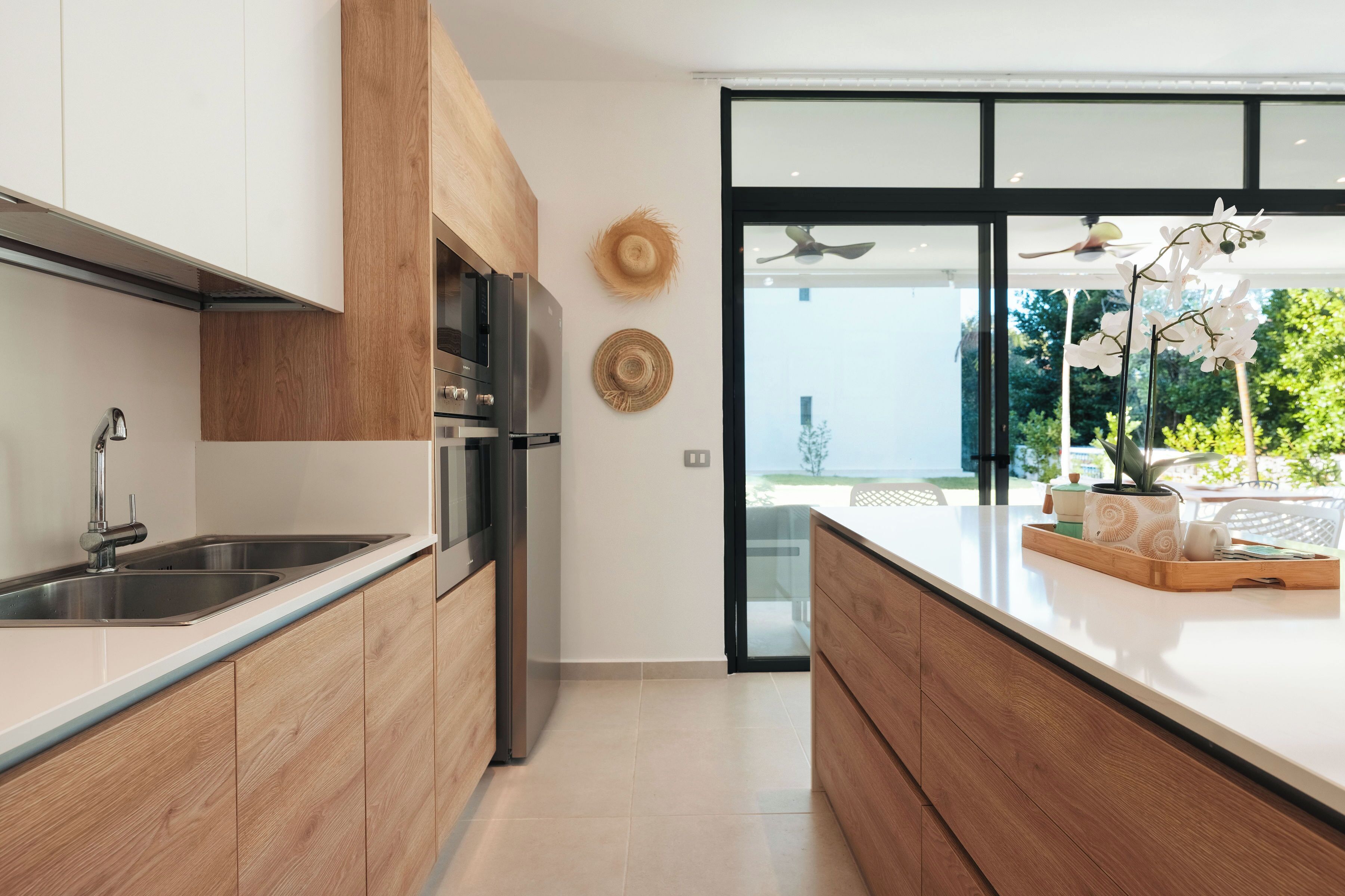Een moderne keuken met houten kastjes, roestvrijstalen apparatuur en een groot eiland met een schaal vol spullen.