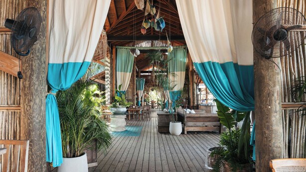 A wooden deck with potted plants, a wooden bench, and a hanging fan. - Sol de Arena Beachfront Condos (Las Terrenas)