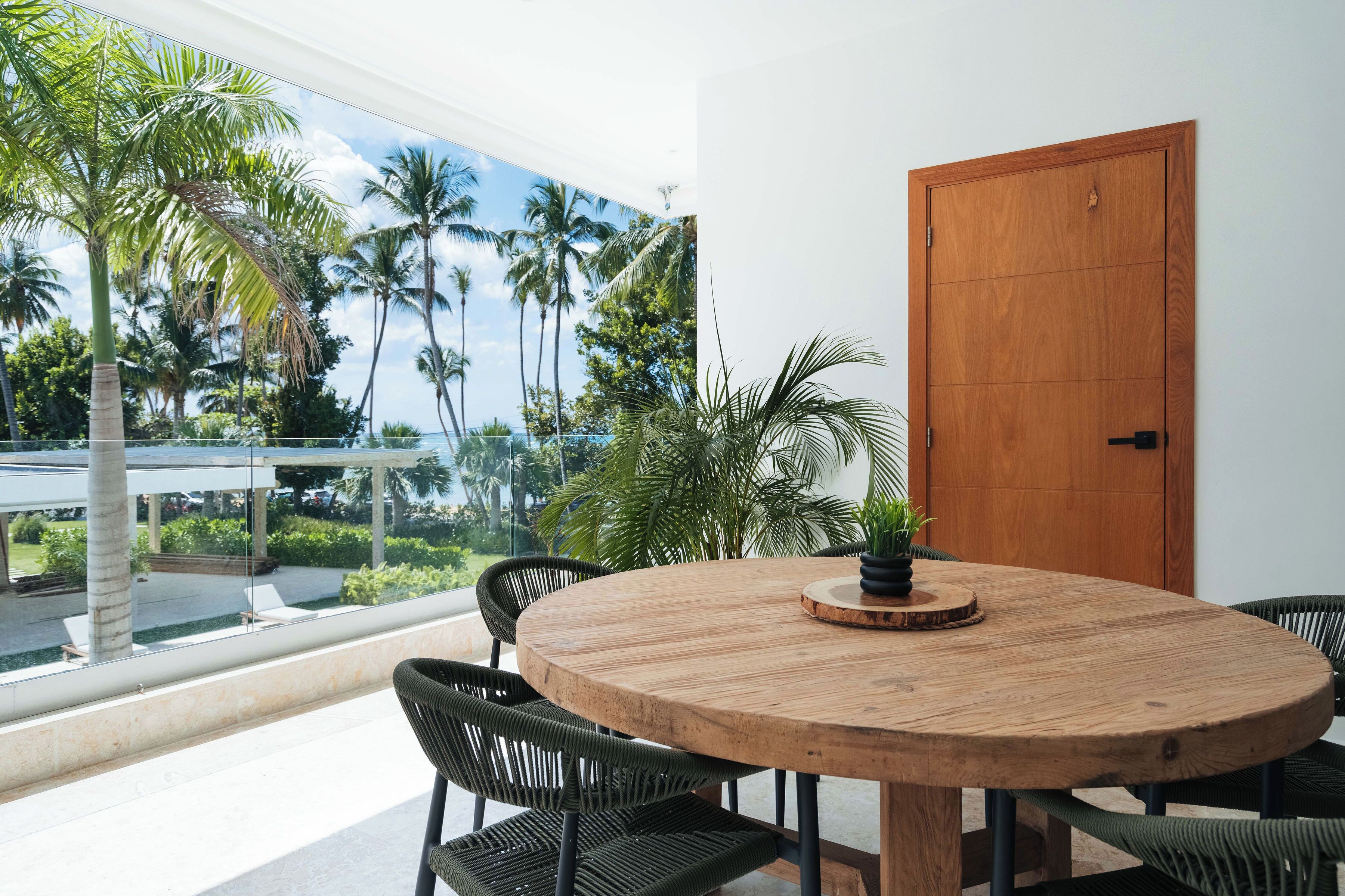 A round wooden table with chairs, a potted plant, and a wooden door.