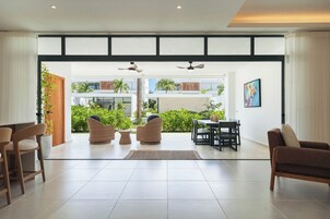 Amplia sala de estar con un ventanal grande, dos ventiladores de techo y vistas al exterior.