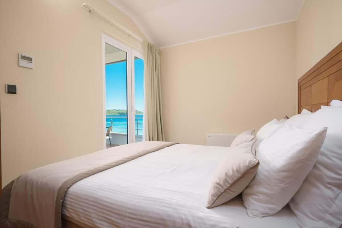 Ein Hotelzimmer mit Bett, Meerblick und einem Vorhangfenster.