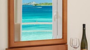 A wooden-framed mirror with a view of a beach and ocean, a wine bottle, and a glass on a wooden dresser. - Hotel Duje (Vodice)