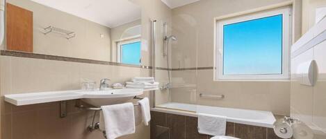 Une salle de bain moderne avec une douche à parois de verre, une grande fenêtre, un lavabo blanc et des toilettes.