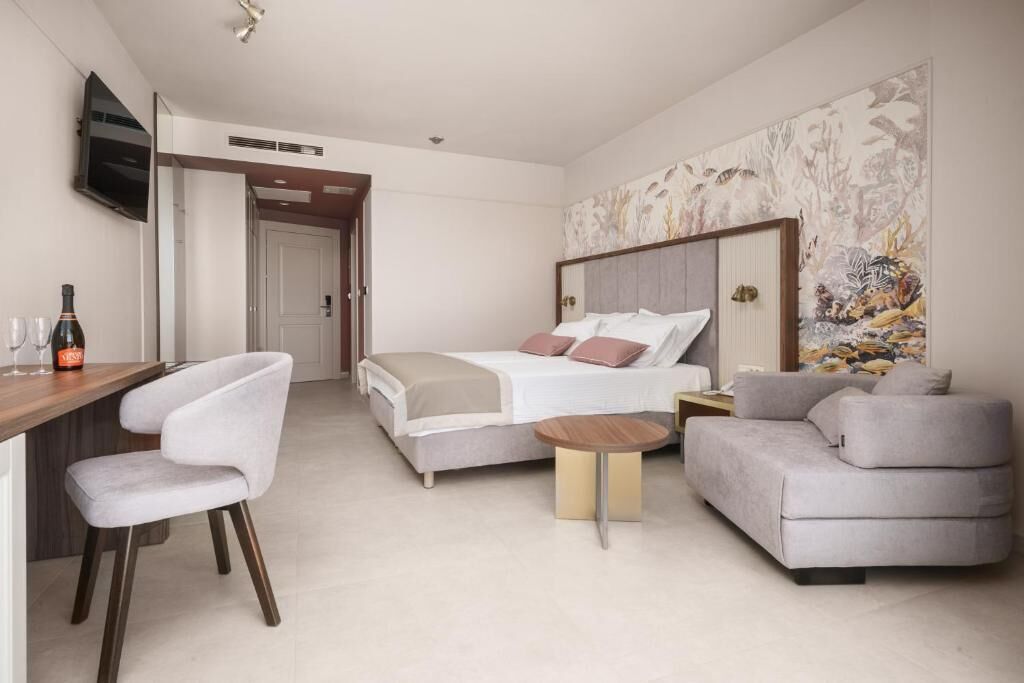 A hotel room with a bed, a sofa, a desk, and a TV.
