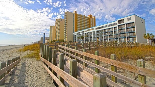 A beachfront hotel with multiple high-rise buildings, a wooden boardwalk, and a sandy beach. - Perfect 2-bedroom apartment with AC in North Myrtle Beach peppertree (North Myrtle Beach)