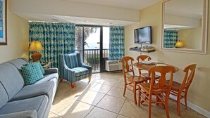 A room with a sofa, chairs, a dining table, a TV, and a large mirror. - Perfect 2-bedroom apartment with AC in North Myrtle Beach peppertree (North Myrtle Beach)