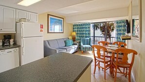 A compact kitchen with a refrigerator, a dining area with wooden chairs, a sofa, and a view of the outdoors through a sliding door. - Perfect 2-bedroom apartment with AC in North Myrtle Beach peppertree (North Myrtle Beach)