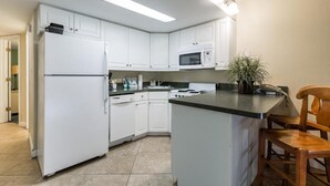A kitchen with white cabinets, a microwave, a stove, and a sink. - Perfect 2-bedroom apartment with AC in North Myrtle Beach peppertree (North Myrtle Beach)