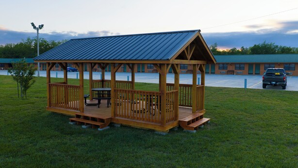 A wooden gazebo with a metal roof, picnic tables, and benches. - Grand Lake Casino Lodge (Grove)