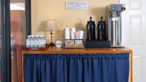 A hotel reception area with a coffee machine, water bottles, and a sign indicating the bar is open daily. - Grand Lake Casino Lodge (Grove)