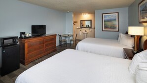 A hotel room with two beds, a desk with a chair, a dresser, a television, a microwave, a sink, and a painting on the wall. - Grand Lake Casino Lodge (Grove)