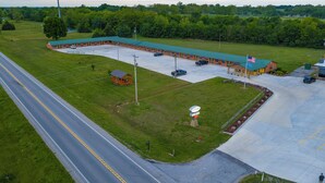 An aerial view of a motel with a green roof, a parking lot, and a small adjacent building. - Grand Lake Casino Lodge (Grove)