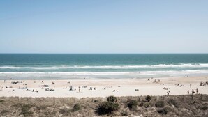 Ein Strand mit badenden und sonnenden Personen.