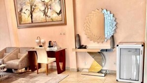 Een moderne woonkamer met een beige bank, een eettafel, een televisie en een decoratief kunstwerk aan de muur.