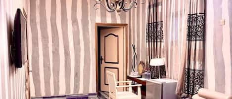 A living room with striped wallpaper, a chandelier, a sofa, a coffee table, and a TV.