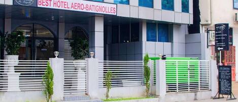A hotel with a modern facade, a prominent sign reading 'BEST HÔTEL AERO-BATIGNOLLES,' and a gated entrance with a green gate.