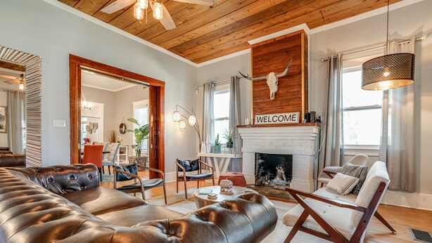 A living room with a fireplace, leather sofa, and a 'WELCOME' sign above it. - Casa Azul. Ideal for groups of 8+. 5 bdr / 4 bath (San Antonio)