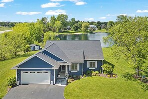 Ein zweistöckiges Haus mit Garage, umgeben von einem gepflegten Rasen und einem See.