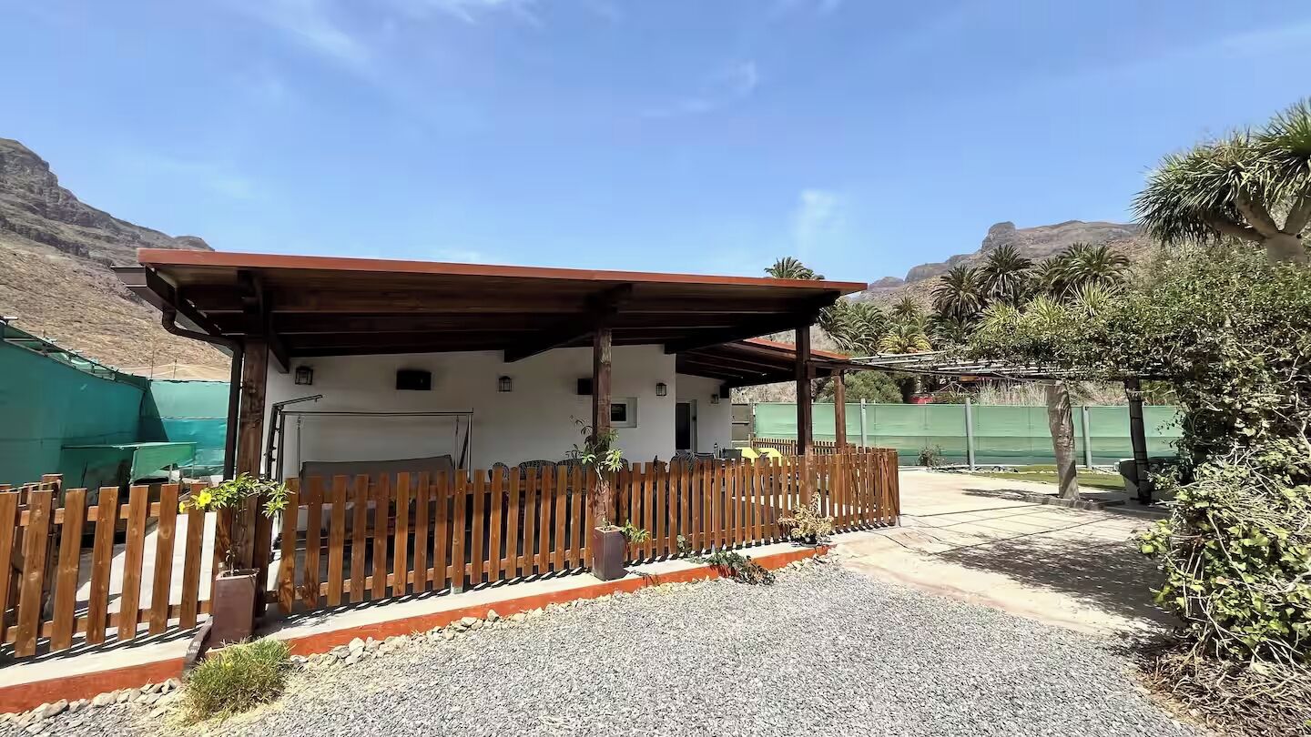 A building with a wooden fence, gravel ground, and a mountain backdrop.