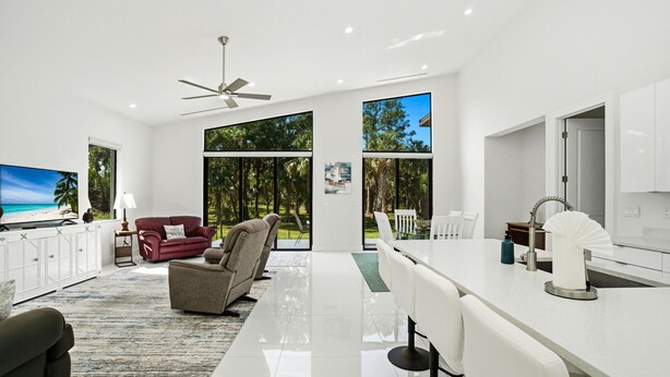 A modern living room with a flat-screen TV, a red sofa, a grey armchair, and a dining area with a white table and chairs. - Christian Nature Haven (Naples)