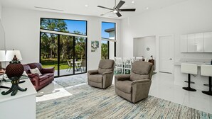 A modern living room with a sofa, two armchairs, a coffee table, and a dining area with chairs and a table. - Christian Nature Haven (Naples)