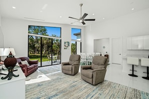 A modern living room with a sofa, two armchairs, a coffee table, and a dining area with chairs and a table. - Christian Haven in Nature (Naples)