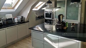 A modern kitchen with skylights, a large island, and stainless steel appliances. - Bail Mobilité, Grand Loft hypercentre de Lille (Lille)