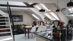 A modern kitchen with skylights, a dining area, and a staircase leading to an upper level. - Bail Mobilité, Grand Loft hypercentre de Lille (Lille)