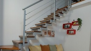 A modern interior with a staircase, wooden benches, a sofa, and wall art. - LOFT HISTORICAL CENTER CATANIA WITH PRIVATE COURTYARD (Catania)