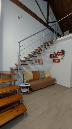 Ein modernes Interieur mit einer Treppe, Holzbanken, einer Couch und Wandkunst.